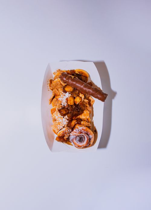 Free A scrumptious cinnamon roll topped with a chocolate bar and caramelized nuts in a white tray. Stock Photo