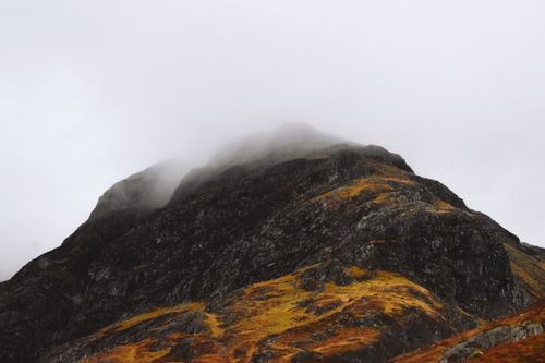 Free Majestic mist-covered mountain peak in the Scottish Highlands, showcasing rugged natural beauty. Stock Photo