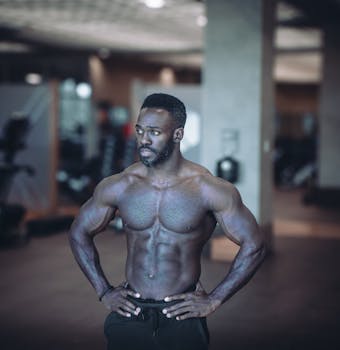 Muscular man confidently posing in a gym, showcasing strength and fitness achievements.