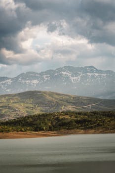 Breathtaking view of a peaceful mountain range and calm lake on a cloudy day.