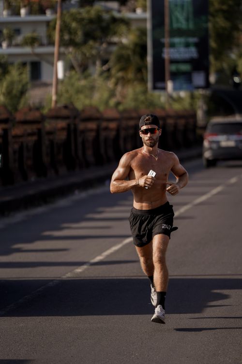 Free A fit man jogging on a city street showing determination and healthy lifestyle. Stock Photo