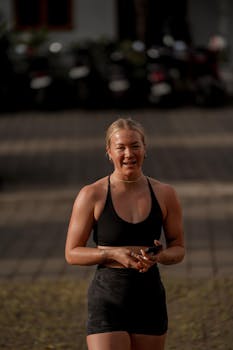Smiling woman in athletic wear during an outdoor workout on a sunny day.