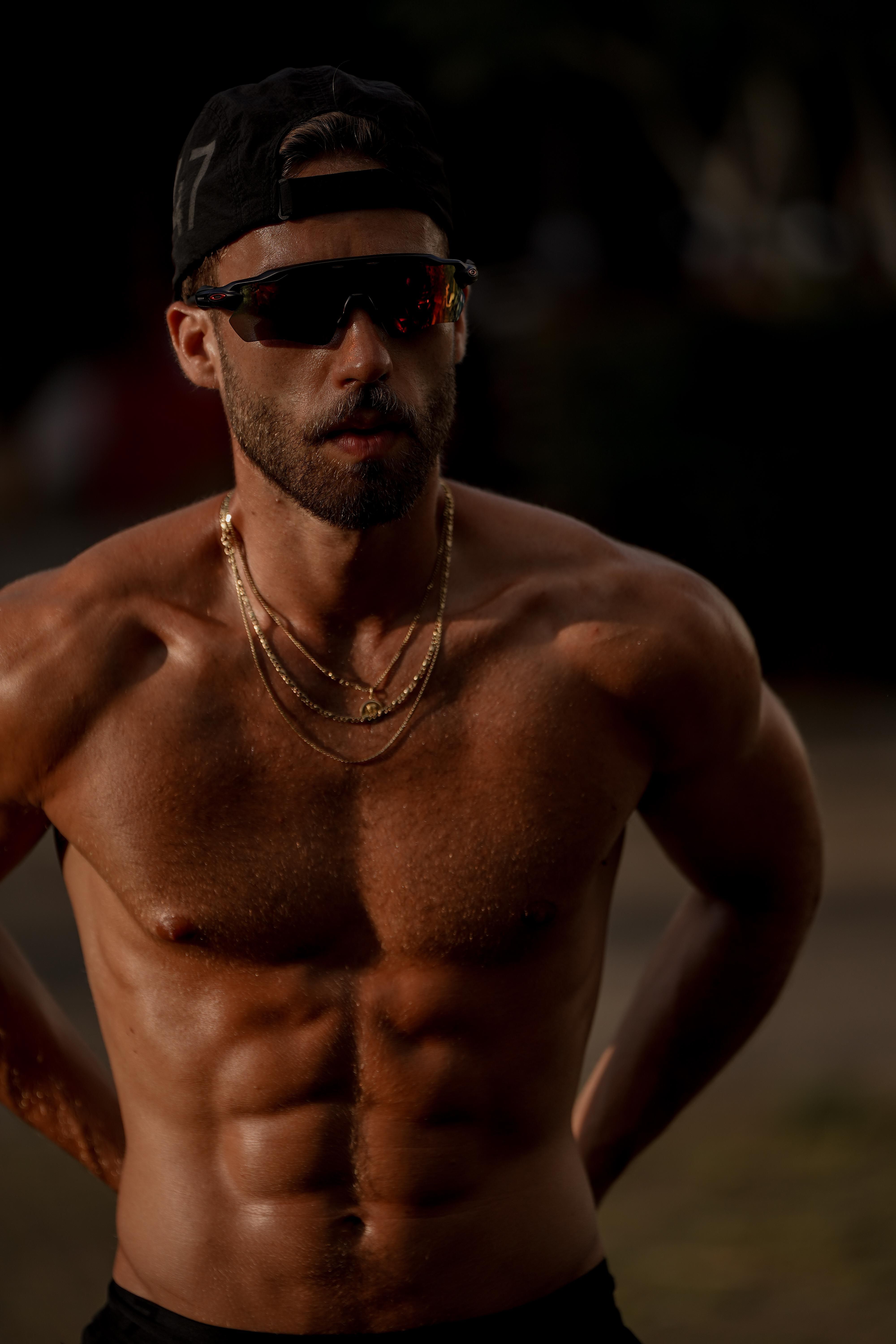 Muscular male athlete poses confidently outdoors, showing fitness and strength.