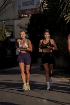 Two women running on a city street, embodying fitness and determination.