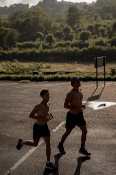 Two men jogging on a country road amidst lush greenery, capturing a healthy lifestyle moment.