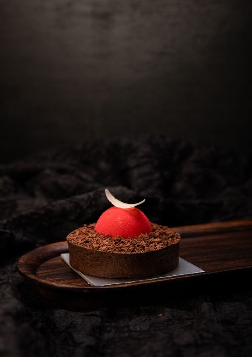 Free Luxurious chocolate dessert with red glaze and garnish, styled on a dark wooden platter. Stock Photo