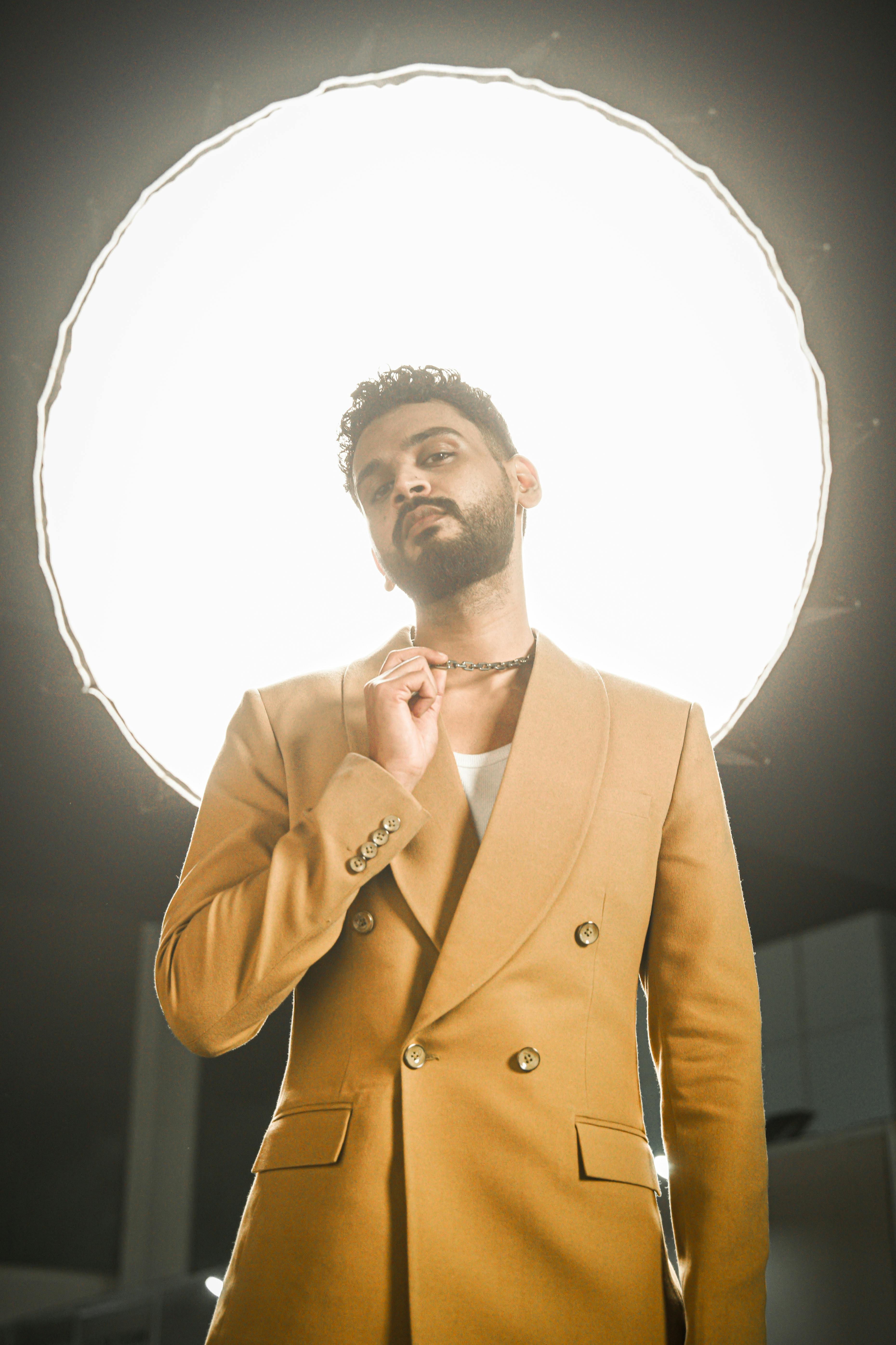 Portrait of a confident male model in a brown blazer under studio lighting.