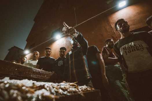 A bustling night scene at a fish market in Ras El-Bar, Egypt, with local fishermen.