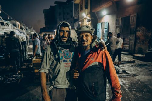 Free Two fishermen posing at a vibrant night fish market in Ras El-Bar, Egypt. Stock Photo