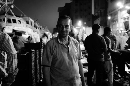 Free Nighttime street photo capturing local life in Ras El-Bar, Egypt with fishermen and boats. Stock Photo