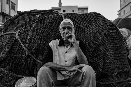 Free Black and white portrait of an elderly fisherman sitting by fishing nets in Ras El-Bar, Egypt. Stock Photo