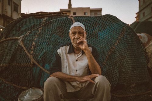 Free Candid portrait of a fisherman sitting in front of fishing nets at sunset in Ras El-Bar, Egypt. Stock Photo
