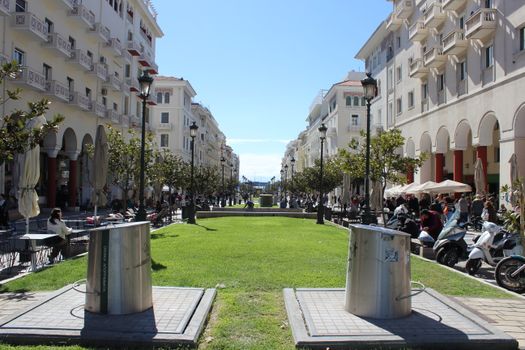 Sunny day at Aristotelous Square in Thessaloniki with people enjoying cafes and shops.