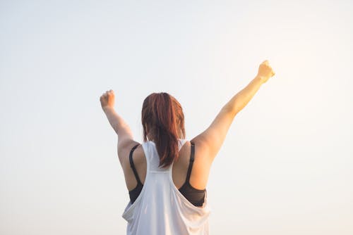 Woman Wearing Black Bra and White Tank Top Raising Both Hands on Top