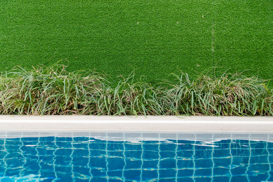Green artificial turf beside a landscaped pool