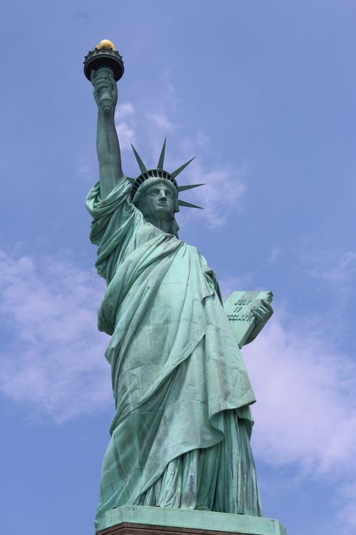 Free Iconic Statue of Liberty under a serene blue sky in New York City. Stock Photo