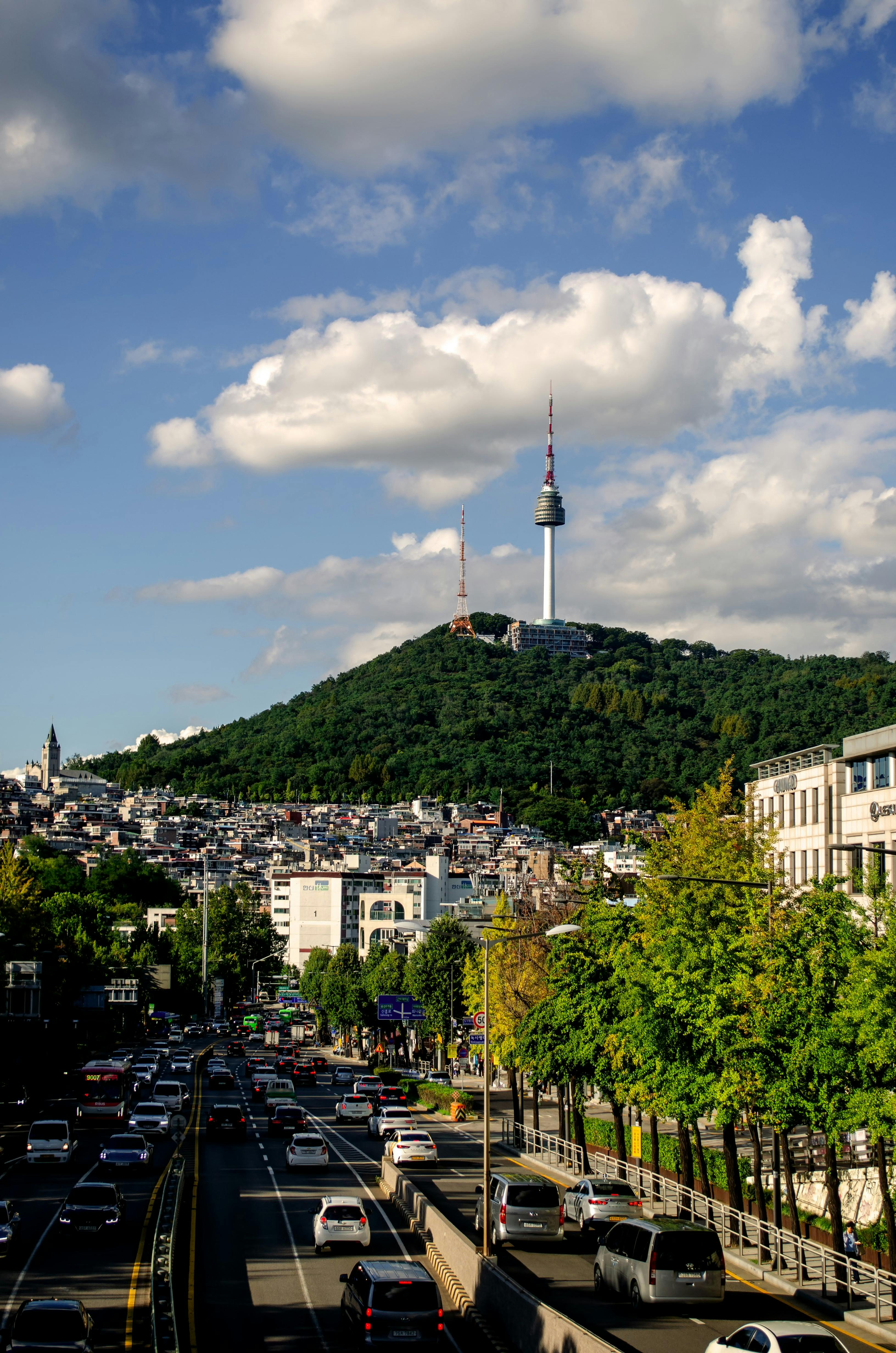 Bright cityscape of Seoul featuring the iconic Namsan Tower on a clear day with bustling streets below.