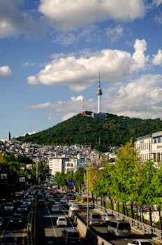 Bright cityscape of Seoul featuring the iconic Namsan Tower on a clear day with bustling streets below.