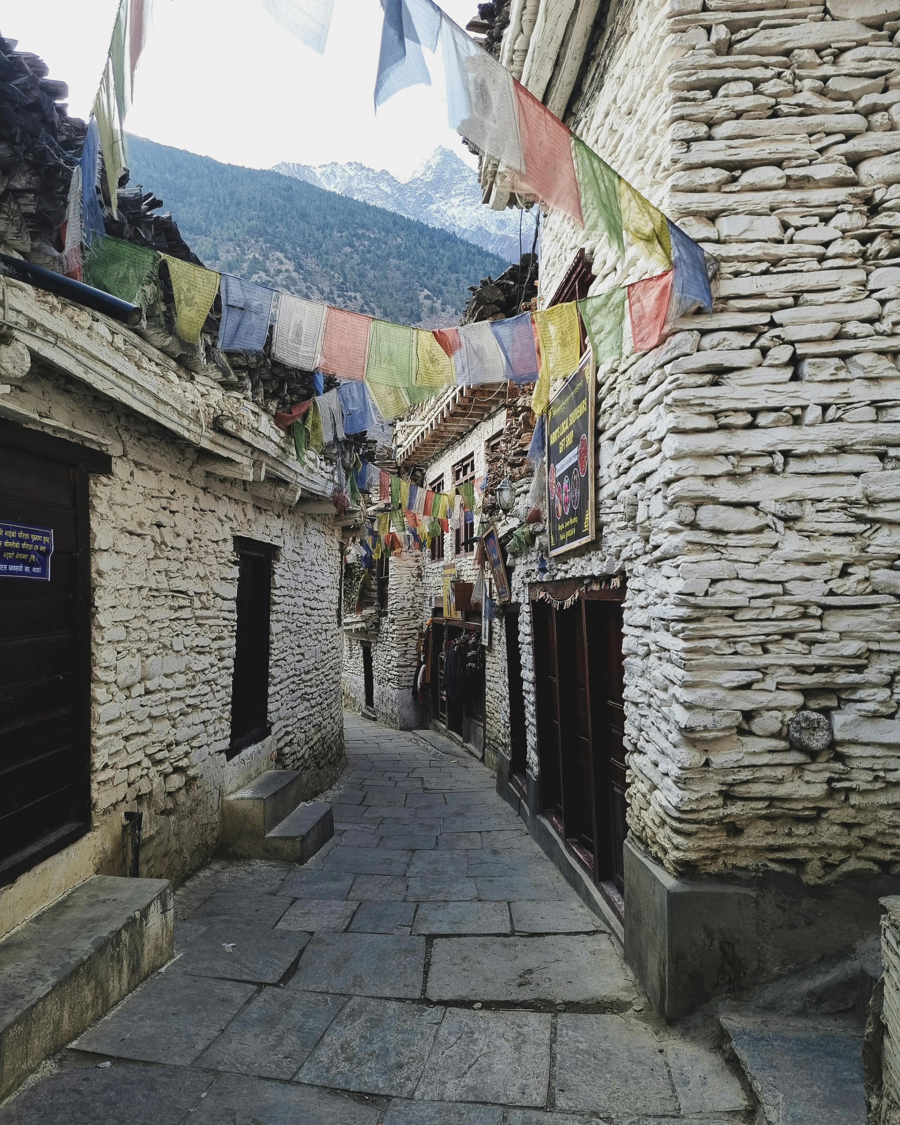 Picturesque stone alleyway with prayer flags in Mustang, Nepal, exuding peace and cultural charm.