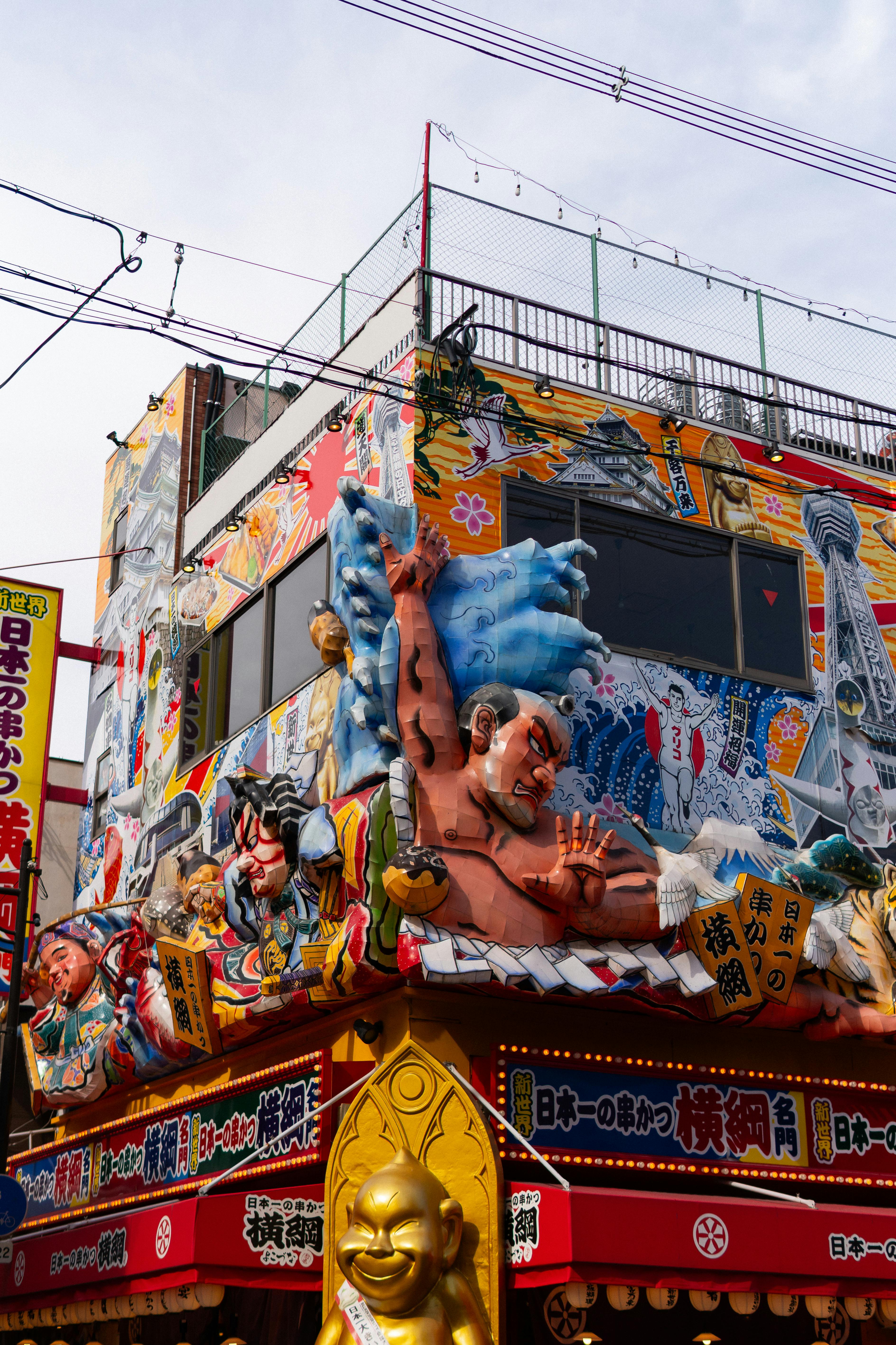 Vibrant Japanese storefront adorned with eclectic statues and colorful art in bustling city.
