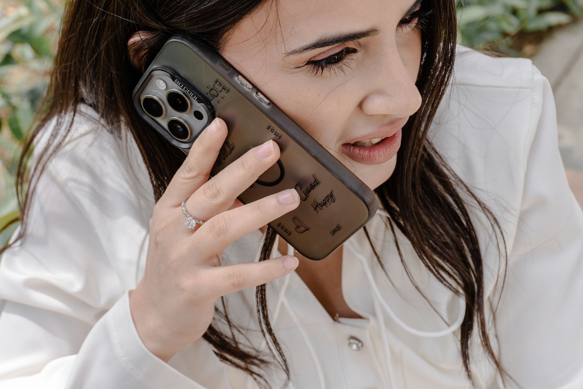Close-up of a woman holding a smartphone to her ear while sitting outdoors, showcasing modern communication.