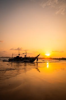 Silhouetted fishing boat at sunset on Weligama Beach, Sri Lanka.