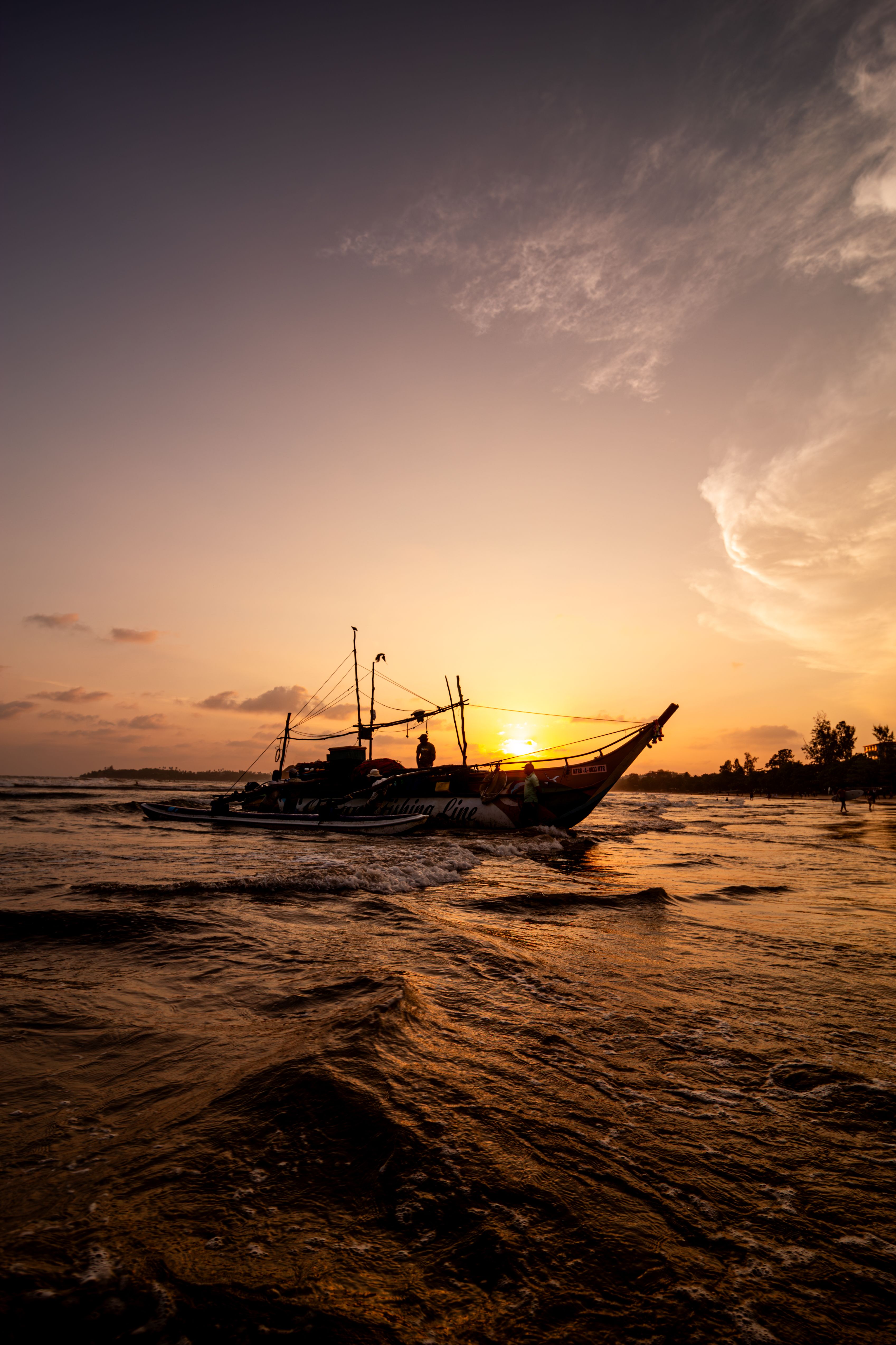 Traditionelles Fischerboot bei Sonnenuntergang in der Bucht von Weligama auf Sri Lanka