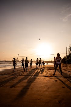 Silhouetted adults playing beach volleyball against a stunning sunset in Weligama, Sri Lanka.