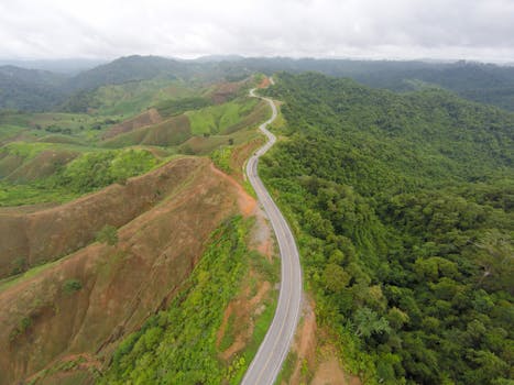 A winding road through lush green mountains in Tambon Nong Chaeng, Thailand.