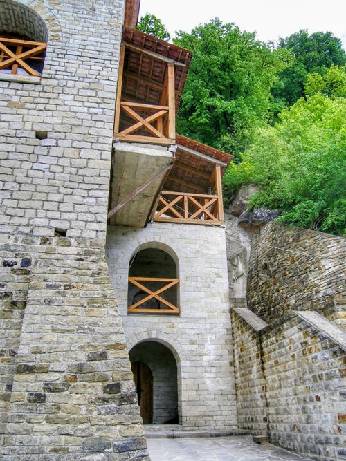 Free Old stone building with wooden balconies nestled among lush greenery. Stock Photo