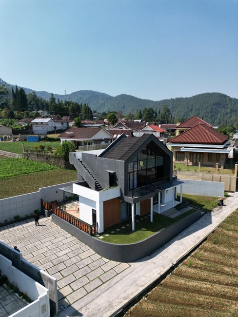 Aerial view of a modern house amidst lush hills in East Java, Indonesia.