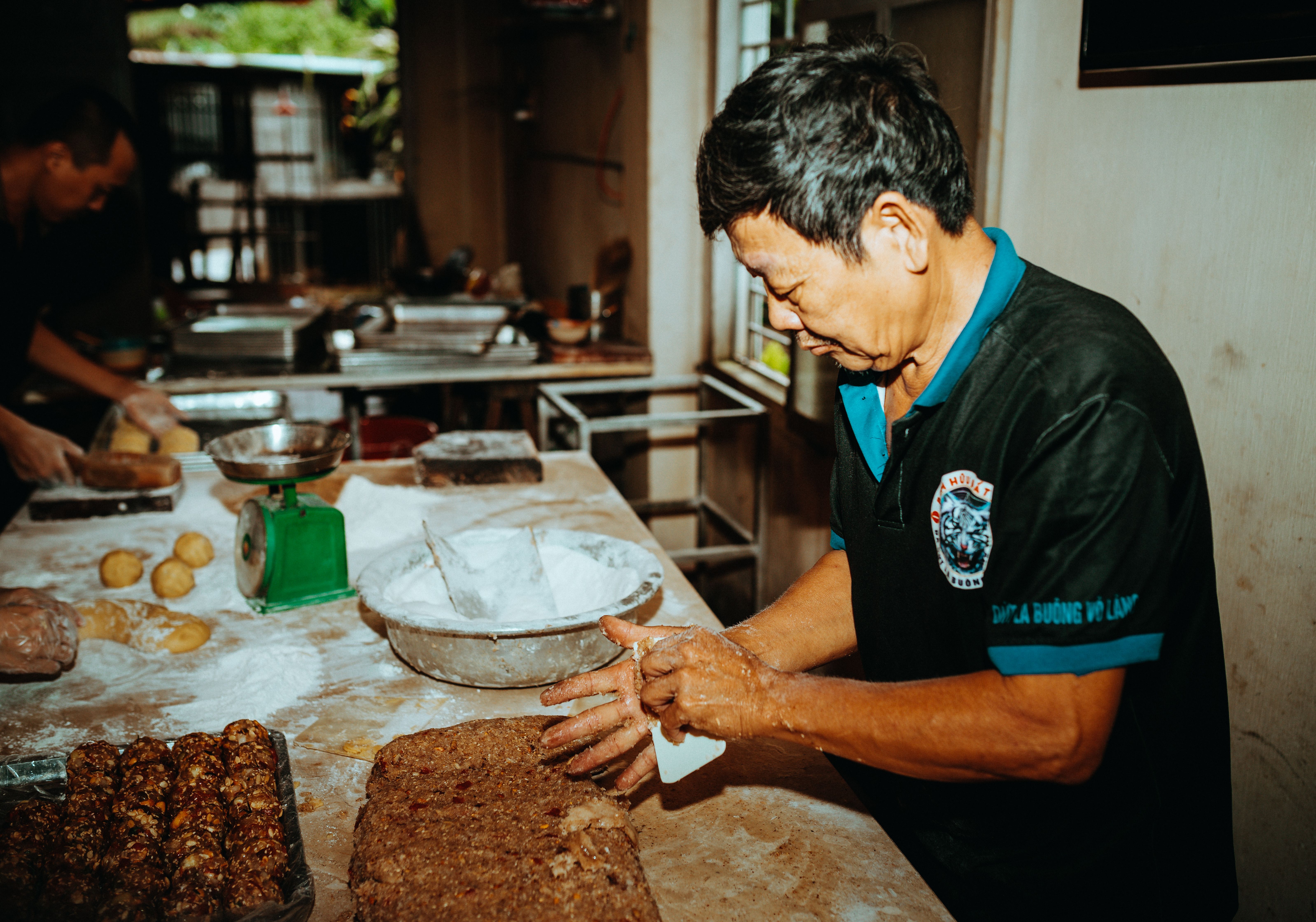 Asian man preparing bread dough in a rustic bakery in Kon Tum, Vietnam.