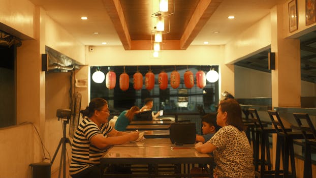 Warm ambiance inside a Japanese restaurant with red lanterns and patrons dining.