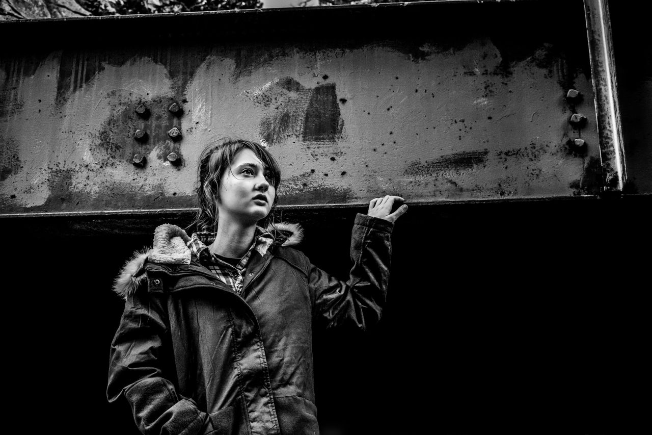 dramatic black and white portrait of a person under a metal structure