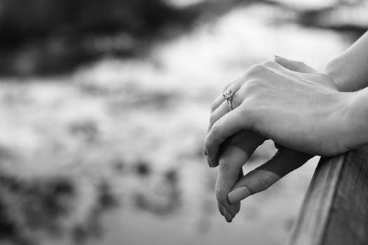 Close-up of hands with an engagement ring in a black and white setting.