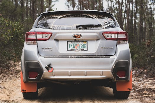 Silver Subaru Crosstrek with Florida plates on forest trail, showcasing outdoor adventure.