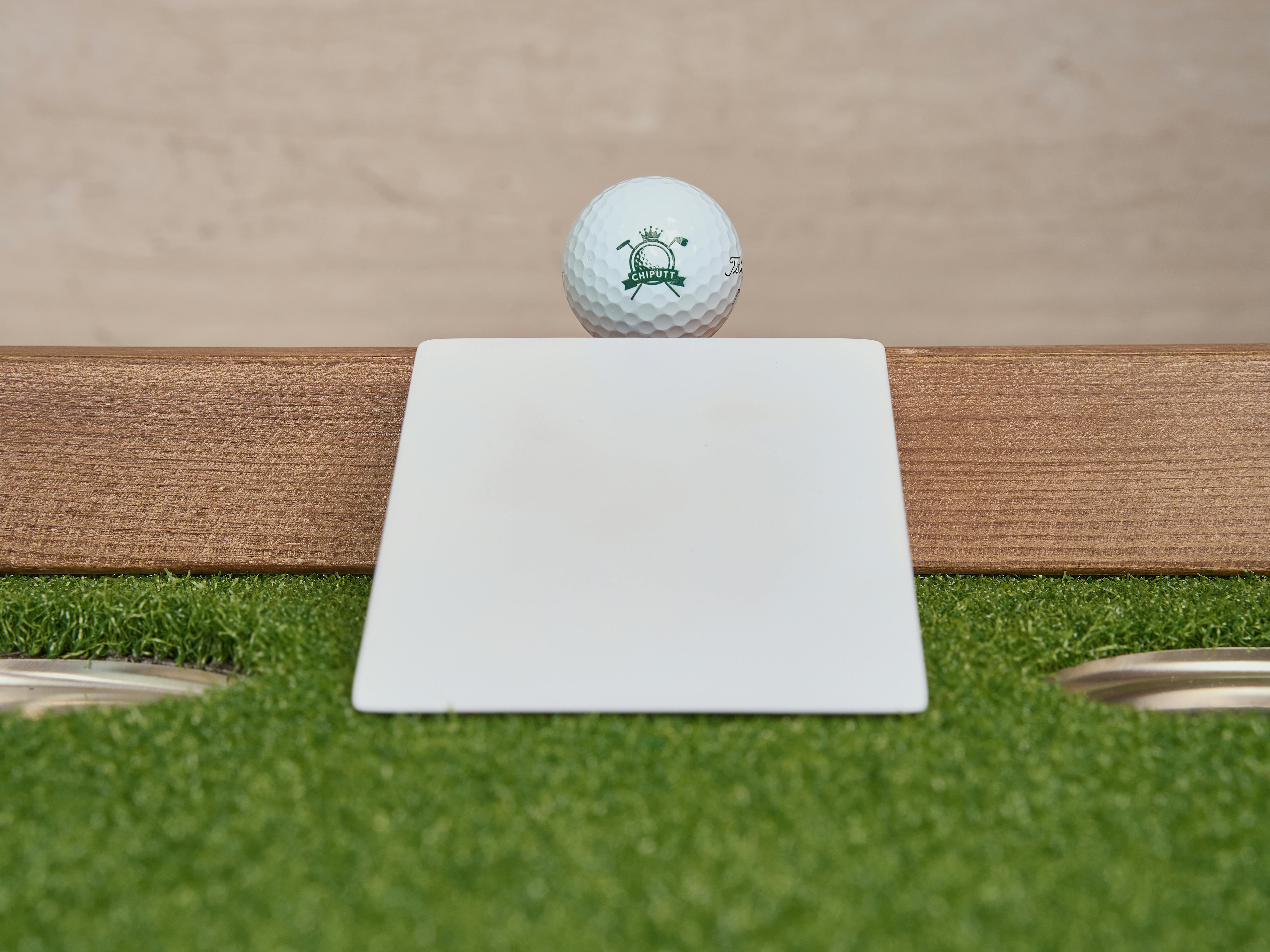 Golf ball positioned on an artificial turf putting green using a training aid for practice.