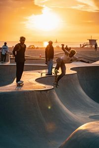 Skateboarders at a beach skate park at sunset, photo by maxed. RAW on Pexels