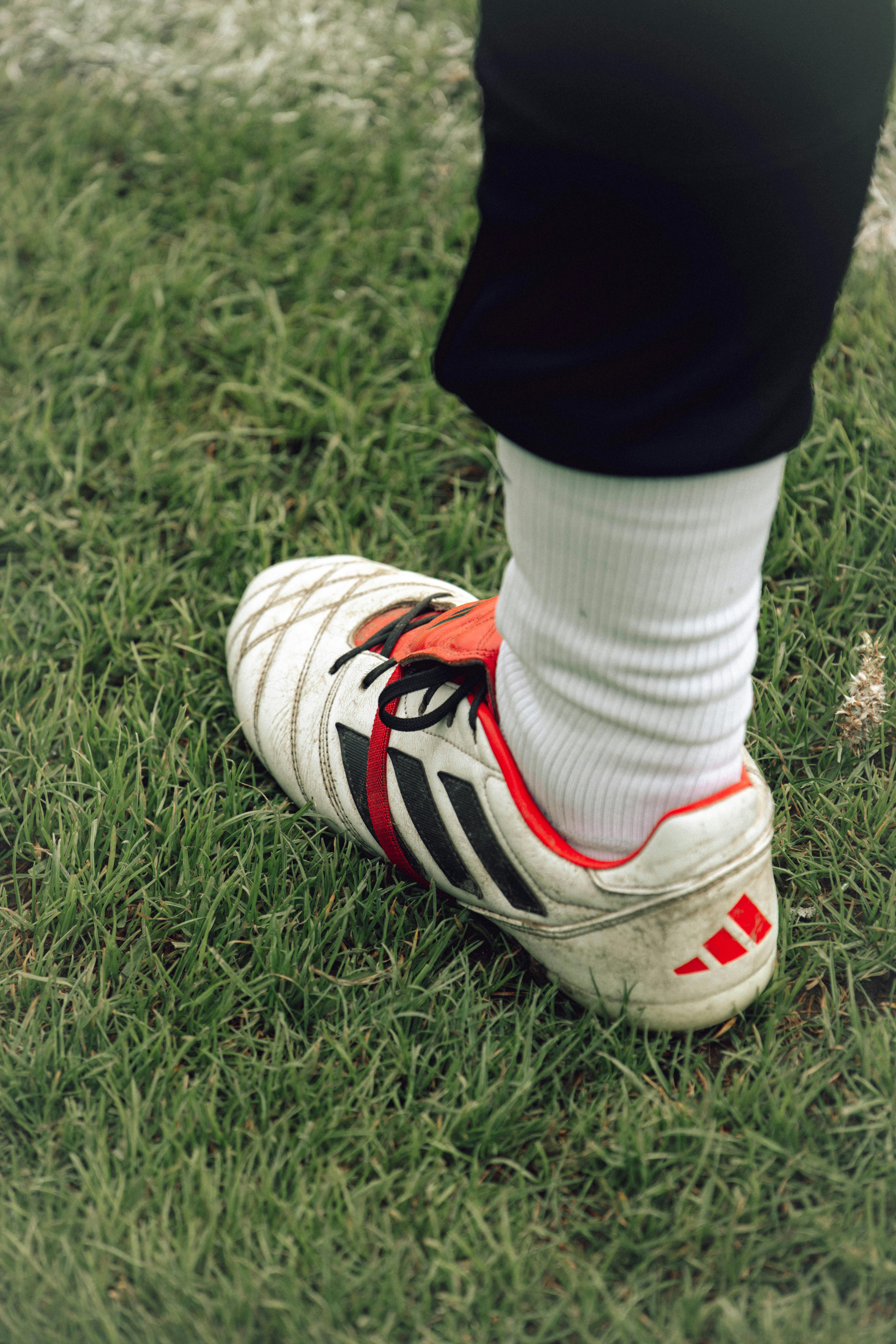 Detailed shot of a soccer shoe worn by a player on a grass field.