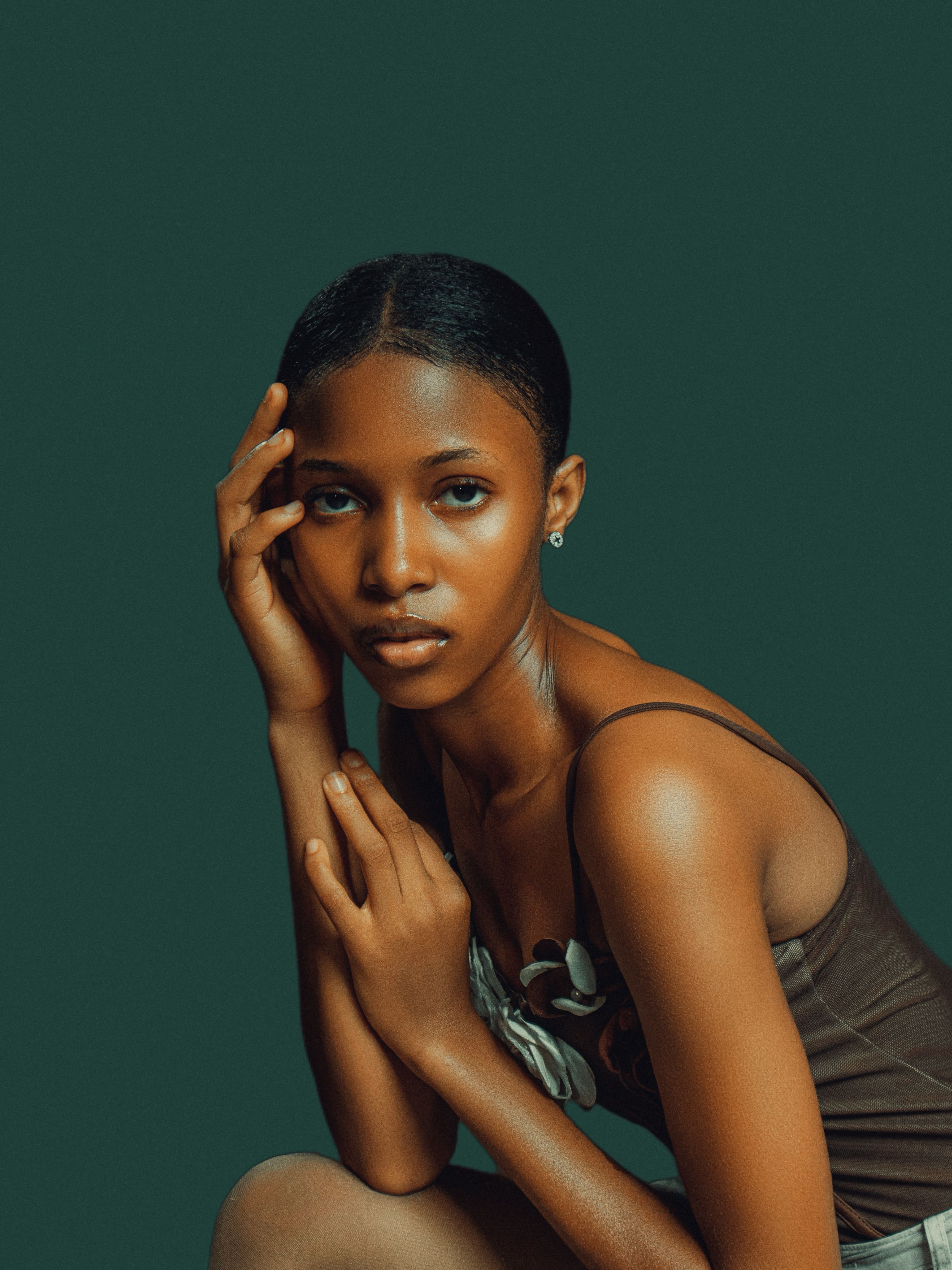 Artistic portrait of a young woman against an olive green background, showcasing elegance.