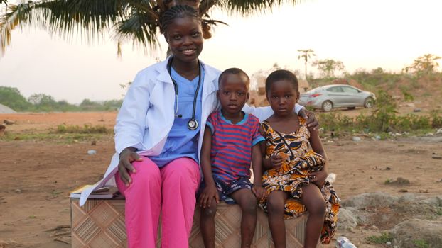 Photo by Khanh Hoang Minh 2 Female healthcare worker smiles with two children outside, showcasing community care.