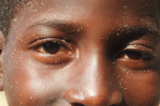 A detailed close-up shot of a child's face with sand, highlighting eyes and texture.