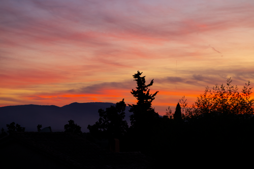 Free Vibrant sunset sky with silhouetted trees and hills in a tranquil setting. Stock Photo