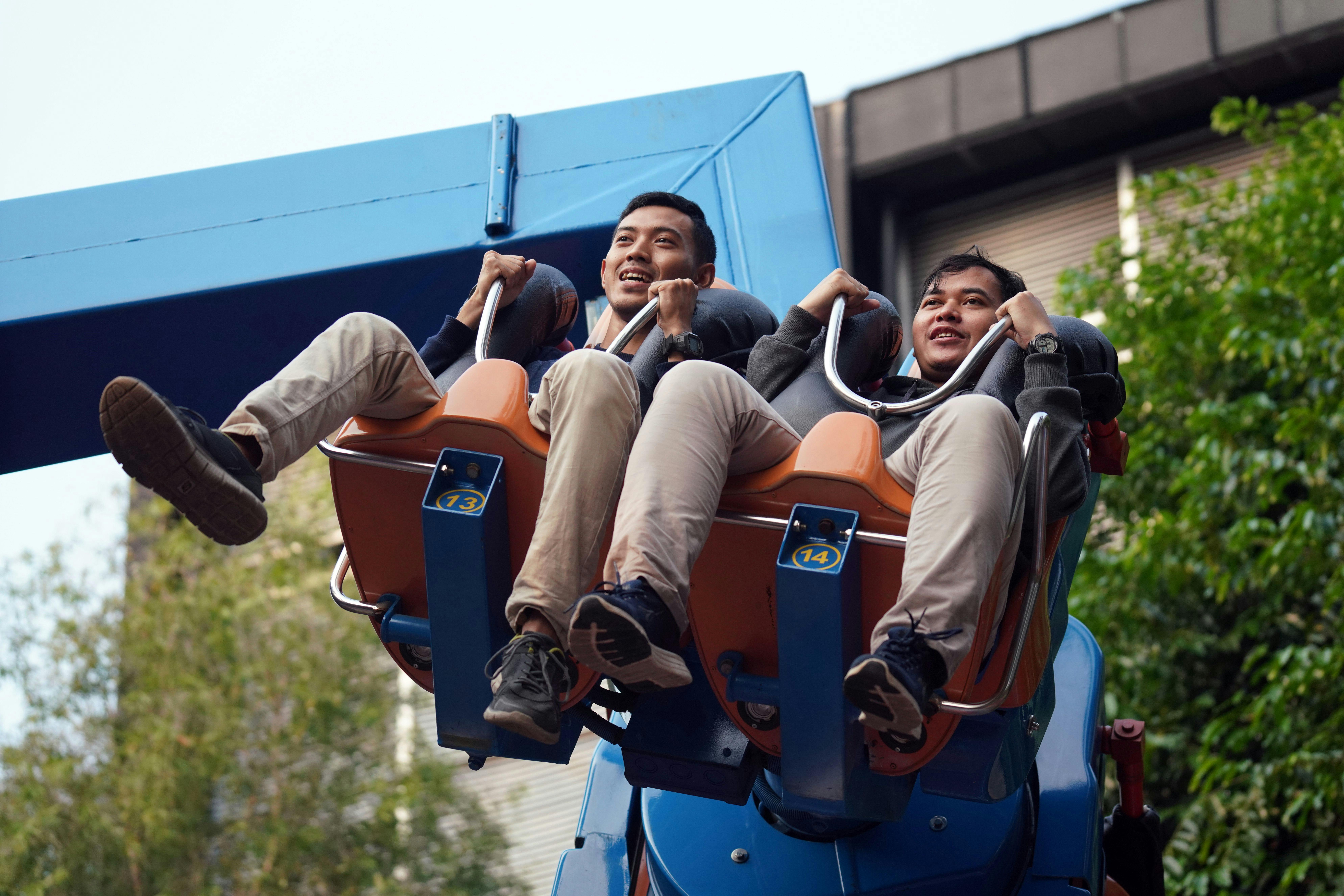 Two men enjoying a thrilling ride at an amusement park, captured mid-air.