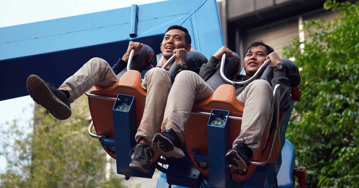 Two men enjoying a thrilling ride at an amusement park, captured mid-air.