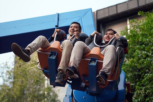 Two men enjoying a thrilling ride at an amusement park, captured mid-air.