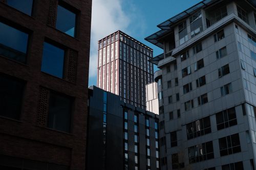 Free A view of modern skyscrapers framed by contemporary buildings under a clear blue sky. Stock Photo
