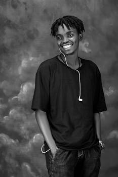 A young man smiling with headphones in a black and white portrait, creating a cool and vibrant mood.