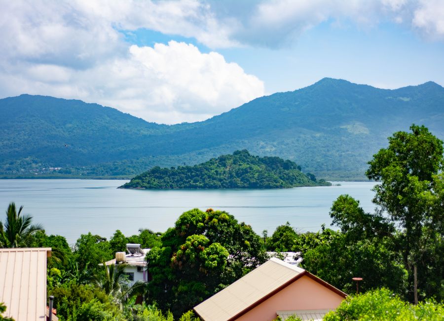 Beautiful landscape of an islet surrounded by the Indian Ocean in Mayotte, showcasing lush greenery and mountains.