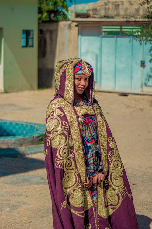 Free Smiling woman wearing ornate African garments standing outdoors on a sunny day. Stock Photo